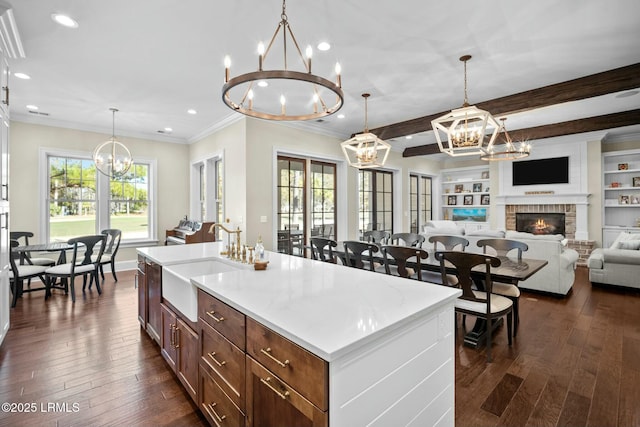 kitchen with hanging light fixtures, sink, a center island with sink, and a chandelier