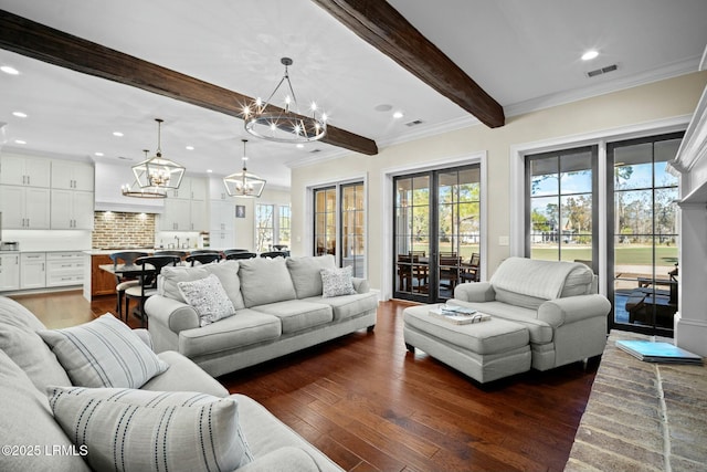 living room featuring dark wood-type flooring, a notable chandelier, beam ceiling, and a wealth of natural light