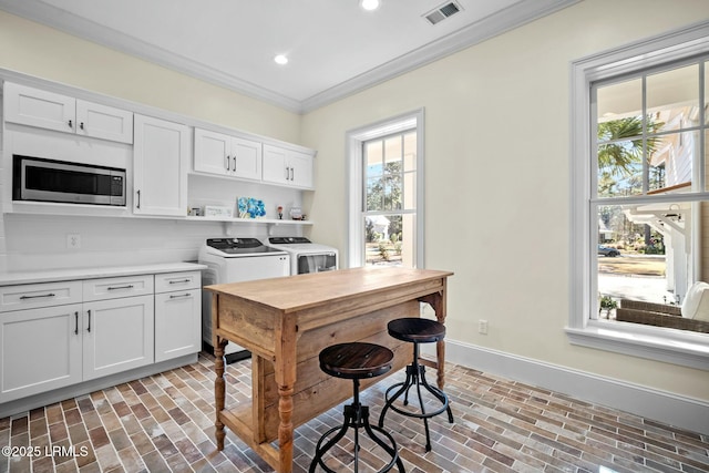 kitchen with white cabinetry, independent washer and dryer, ornamental molding, and stainless steel microwave