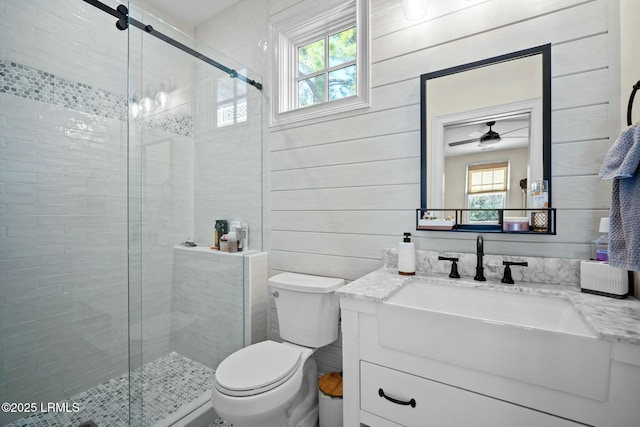 bathroom featuring toilet, wooden walls, a shower with shower door, and a wealth of natural light