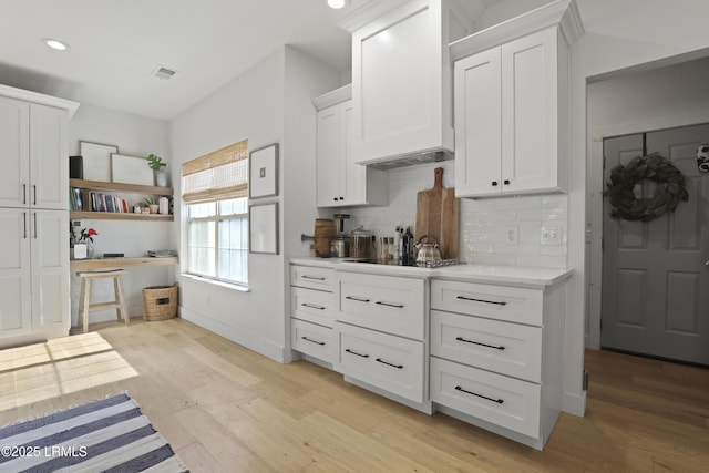 5 Canebrake Ln, Bluffton, SC 29910 - kitchen featuring custom exhaust hood, light countertops, backsplash, white cabinetry, and light wood finished floors