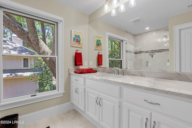 bathroom with a shower with door, vanity, a healthy amount of sunlight, and tile patterned flooring