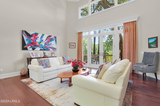 living room featuring plenty of natural light, dark hardwood / wood-style floors, and a high ceiling