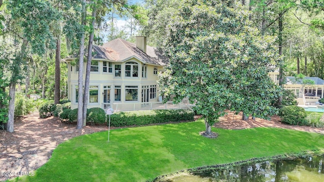 back of property featuring a lawn and a water view