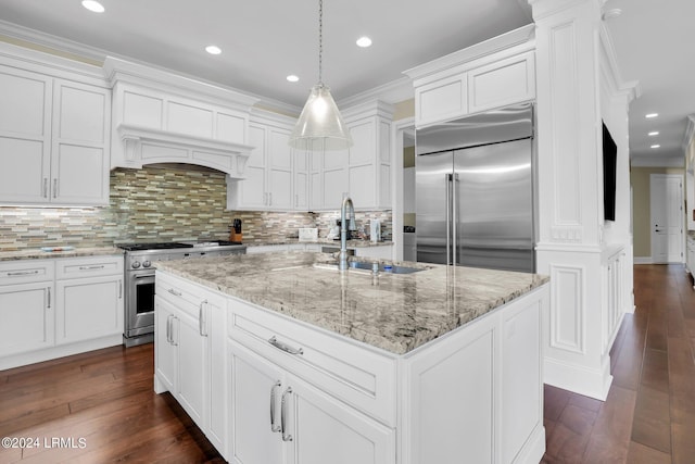 kitchen featuring decorative light fixtures, high quality appliances, tasteful backsplash, sink, and a kitchen island with sink