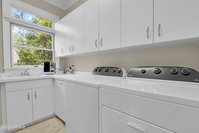 clothes washing area with sink, washing machine and dryer, and cabinets