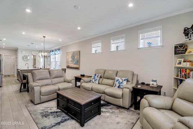 living room featuring ornamental molding, plenty of natural light, a notable chandelier, and light wood-type flooring