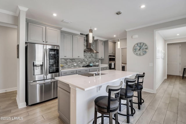 kitchen featuring stainless steel appliances, sink, gray cabinetry, and wall chimney range hood