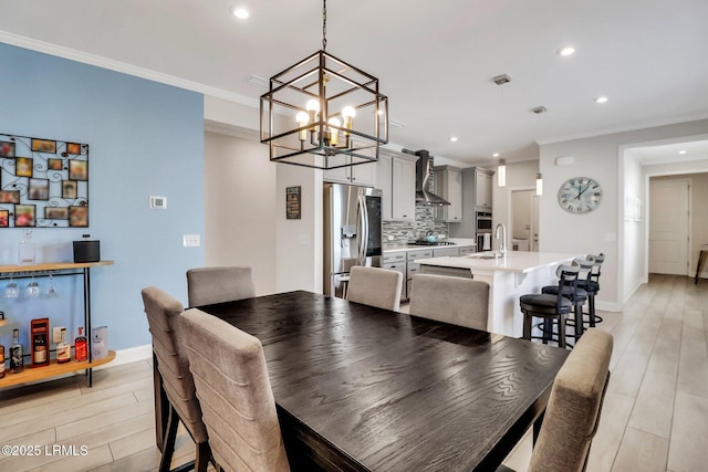 dining room featuring ornamental molding, sink, and light hardwood / wood-style floors