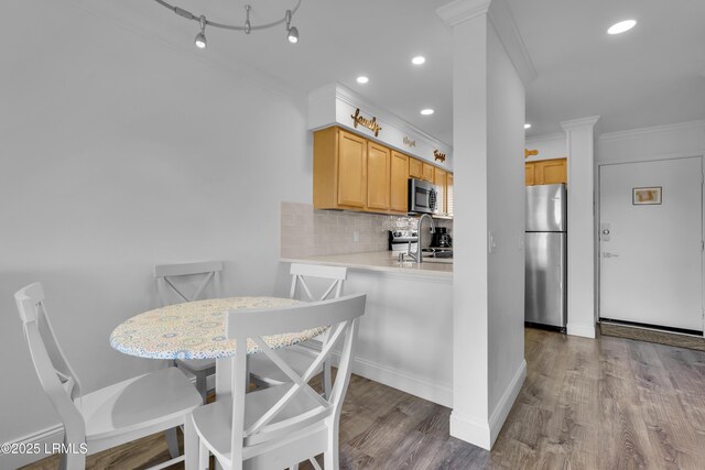 663 William Hilton Pkwy # 2309, Hilton Head Island, SC 29928 - kitchen featuring stainless steel appliances, tasteful backsplash, crown molding, light countertops, and wood finished floors