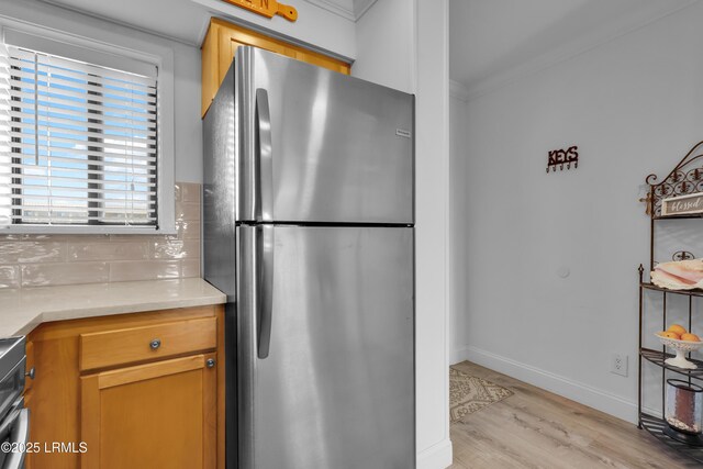 663 William Hilton Pkwy # 2309, Hilton Head Island, SC 29928 - kitchen with light wood-style flooring, freestanding refrigerator, baseboards, ornamental molding, and backsplash