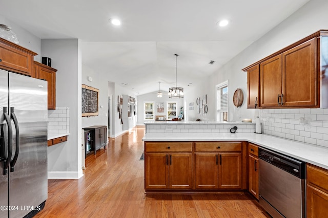 kitchen featuring vaulted ceiling, appliances with stainless steel finishes, tasteful backsplash, hanging light fixtures, and kitchen peninsula