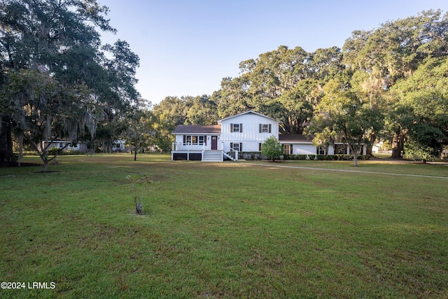 view of front facade featuring board and batten siding, covered porch, and a front lawn