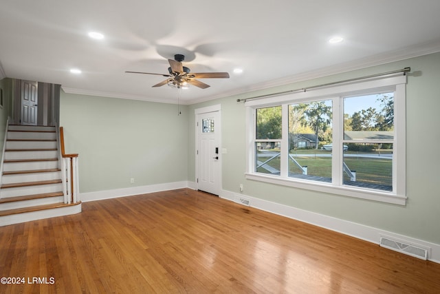 unfurnished living room with stairway, visible vents, light wood finished floors, and ornamental molding