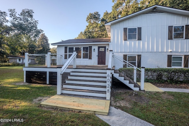 split level home with a deck, brick siding, stairway, a front lawn, and board and batten siding