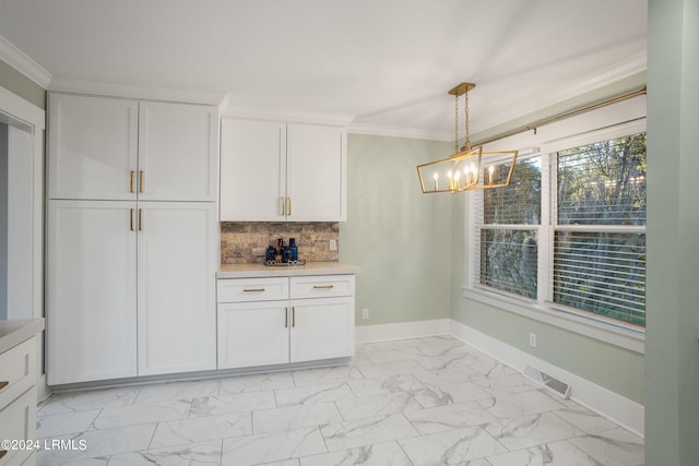 kitchen featuring ornamental molding, marble finish floor, light countertops, and white cabinetry