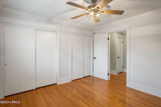 unfurnished bedroom featuring a ceiling fan, baseboards, ornamental molding, light wood-type flooring, and two closets