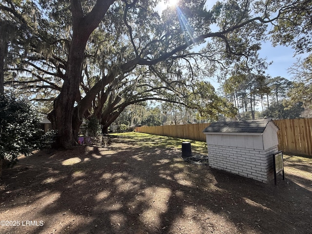 view of yard featuring an outbuilding, fence, and a storage unit