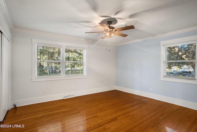 unfurnished room with wood finished floors, a ceiling fan, baseboards, visible vents, and crown molding