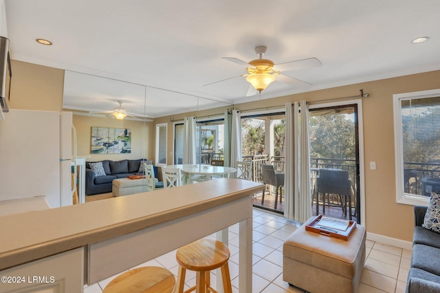 kitchen with light tile patterned floors, a breakfast bar area, ceiling fan, and white fridge