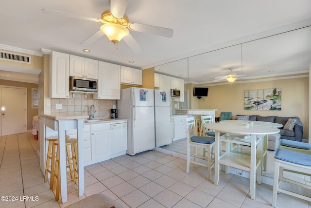 kitchen featuring white cabinetry, white appliances, a kitchen bar, and sink