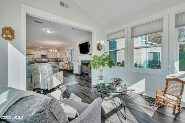 living room with vaulted ceiling, dark hardwood / wood-style floors, and a notable chandelier