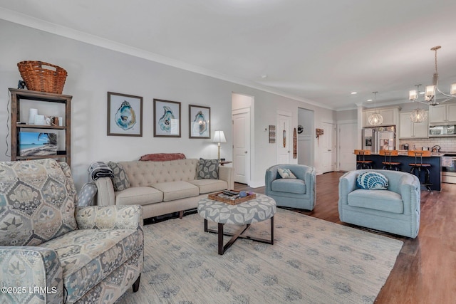 living room with ornamental molding, wood-type flooring, and a chandelier