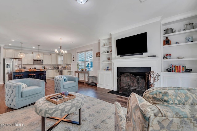 living room with ornamental molding, dark wood-type flooring, a chandelier, and built in shelves