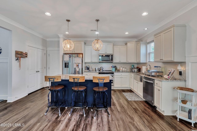 kitchen featuring stainless steel appliances, a center island, light stone counters, dark hardwood / wood-style flooring, and decorative light fixtures