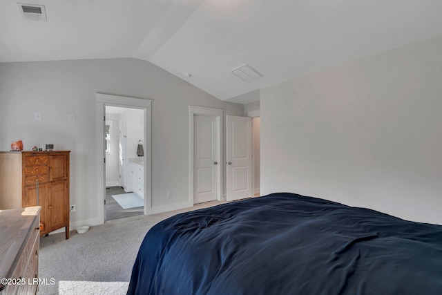 bedroom featuring lofted ceiling, connected bathroom, and light colored carpet