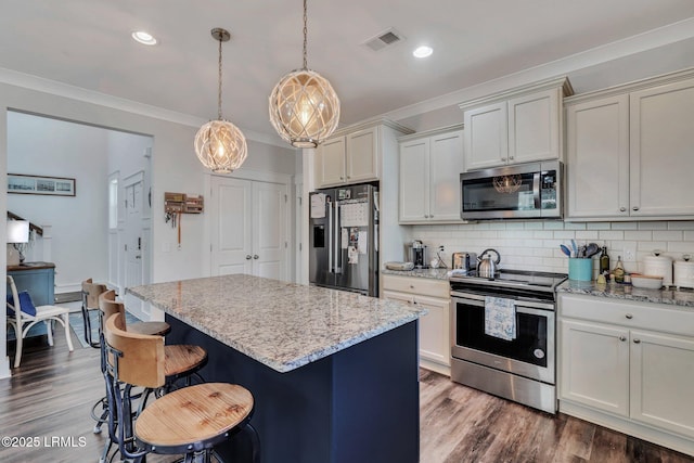 kitchen featuring a kitchen island, appliances with stainless steel finishes, decorative light fixtures, backsplash, and light stone countertops