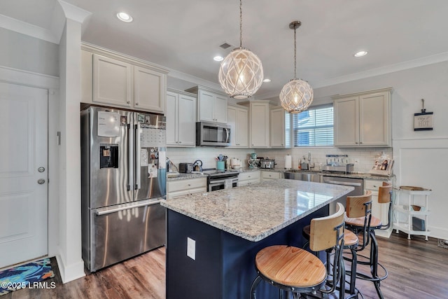 kitchen with light stone counters, decorative light fixtures, a kitchen breakfast bar, a kitchen island, and stainless steel appliances