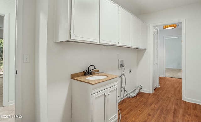 clothes washing area with sink, cabinets, hookup for a washing machine, electric dryer hookup, and light hardwood / wood-style floors