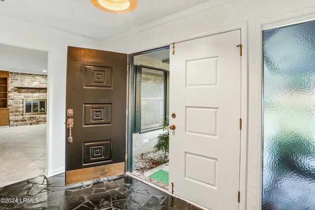 entrance foyer with crown molding and a brick fireplace