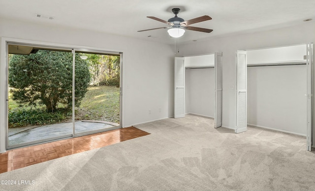 unfurnished bedroom with light carpet, two closets, access to exterior, and ceiling fan