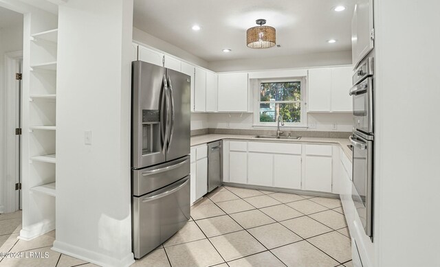 kitchen with white cabinetry, stainless steel appliances, sink, and light tile patterned floors