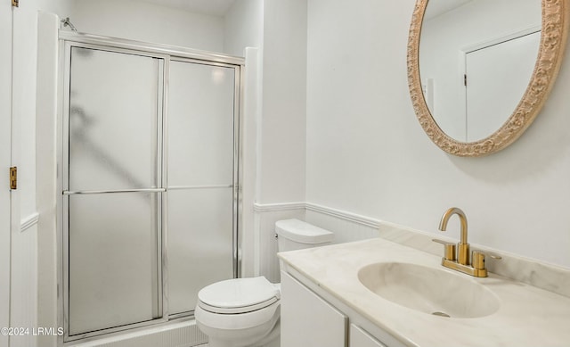 bathroom with a shower with door, vanity, and toilet