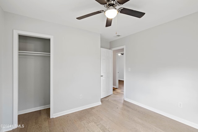 unfurnished bedroom featuring ceiling fan, a closet, and light wood-type flooring