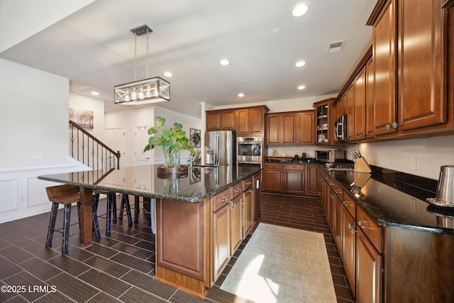 36 Independence Pl, Bluffton, SC 29910 - kitchen featuring appliances with stainless steel finishes, a breakfast bar, brown cabinets, recessed lighting, and a kitchen island with sink