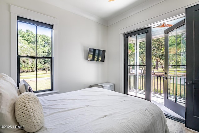 bedroom featuring multiple windows, access to outside, and light hardwood / wood-style floors