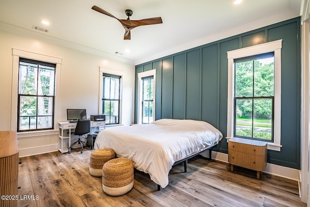 bedroom with hardwood / wood-style flooring, ceiling fan, and multiple windows