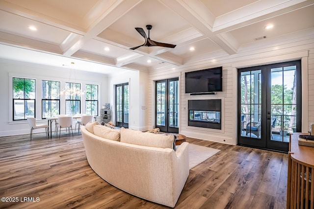 living room with beam ceiling, hardwood / wood-style flooring, and french doors