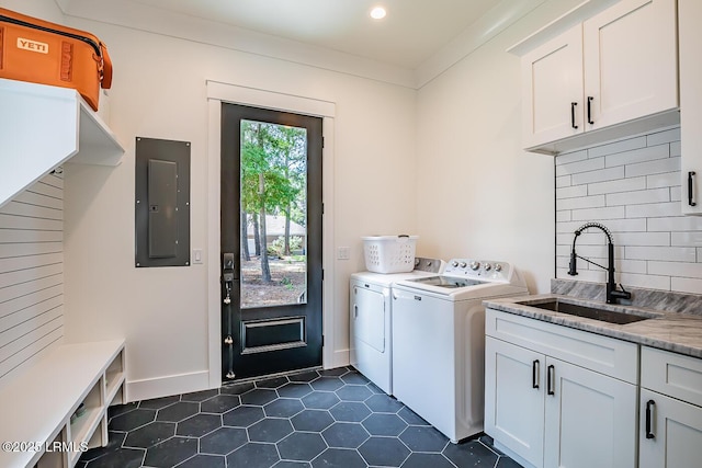 clothes washing area featuring sink, washer and clothes dryer, electric panel, cabinets, and dark tile patterned flooring