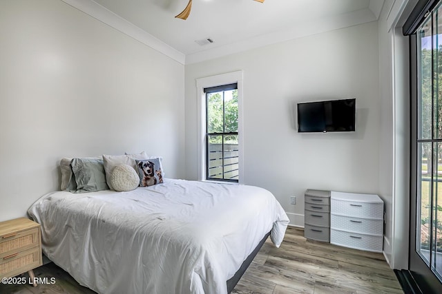 bedroom featuring crown molding, hardwood / wood-style flooring, multiple windows, and ceiling fan