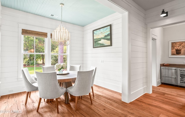 575 Distant Island Dr, Beaufort, SC 29907 - dining space with wood walls, light wood-type flooring, a chandelier, and beverage cooler