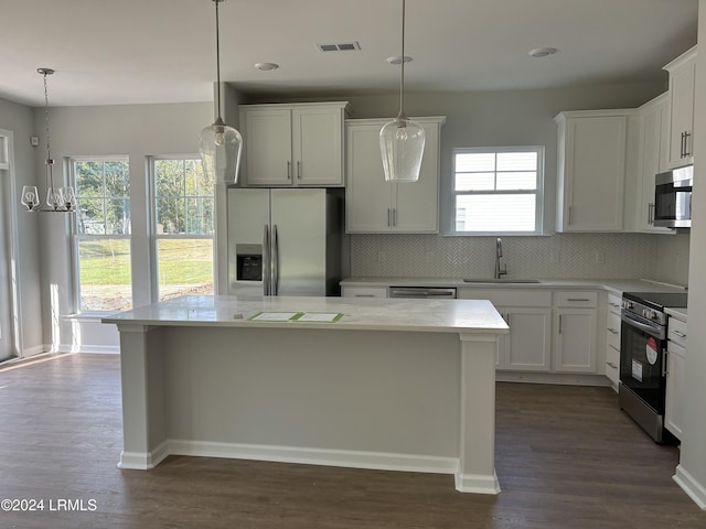 kitchen with pendant lighting, white cabinetry, sink, a center island, and stainless steel appliances