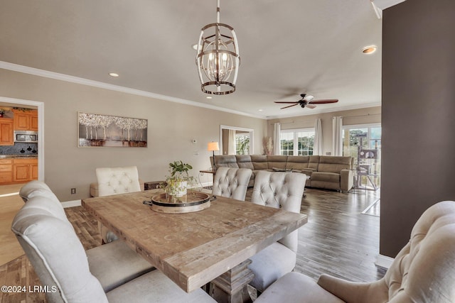 dining space with crown molding, wood-type flooring, and ceiling fan with notable chandelier