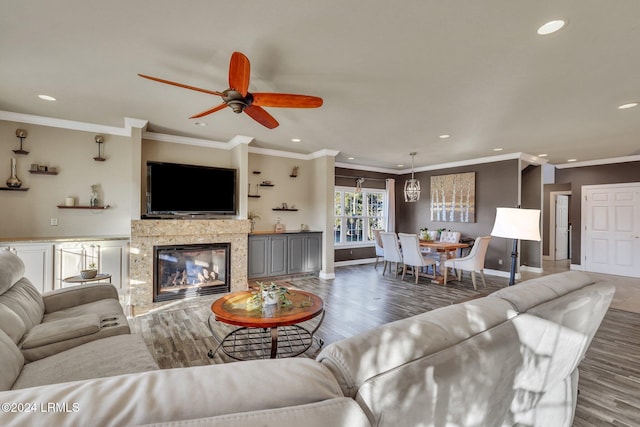 living room with a fireplace, ornamental molding, dark hardwood / wood-style floors, and ceiling fan