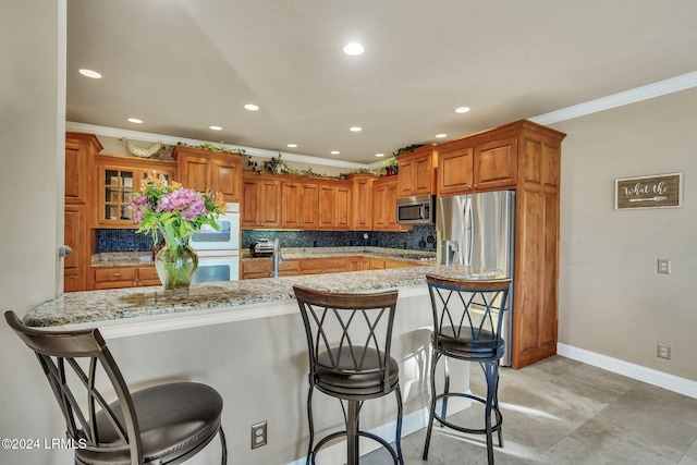 kitchen with light stone countertops, crown molding, stainless steel appliances, and a breakfast bar