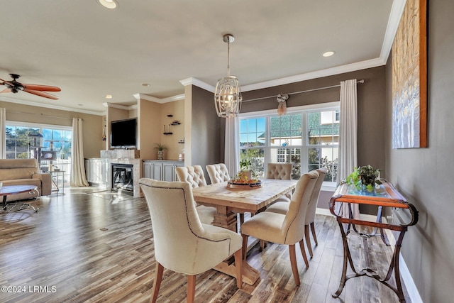 dining area with ceiling fan with notable chandelier, ornamental molding, a healthy amount of sunlight, and light wood-type flooring